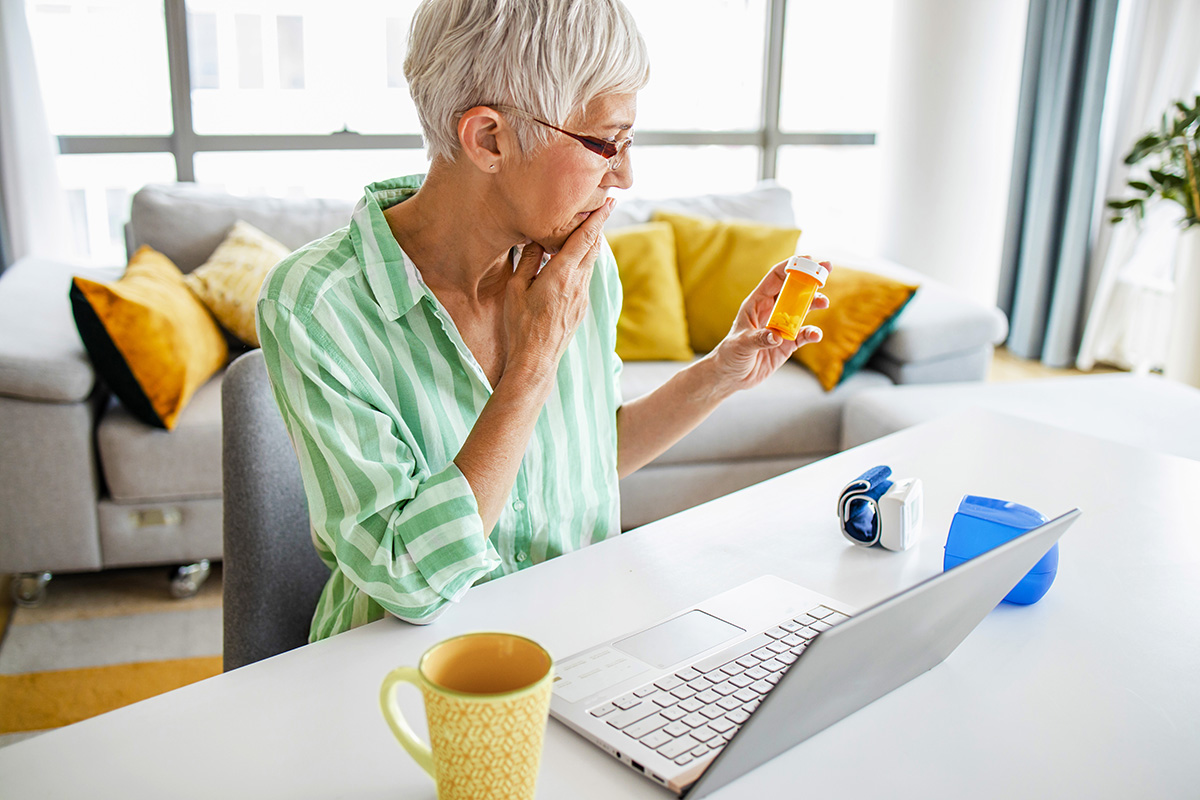 An older woman checks her prescription label to see if her medication has expired.