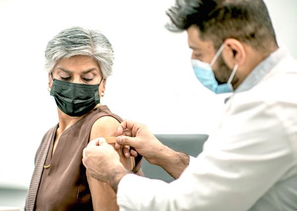 A pharmacist puts a bandage on a woman after giving her a vaccine.