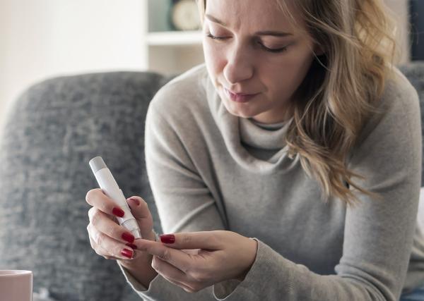 A young woman checks her blood sugar at home.