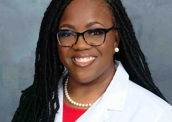 Christina Wilson-Smith, a registered pharmacist with Express Scripts® Pharmacy, smiles in her lab coat.