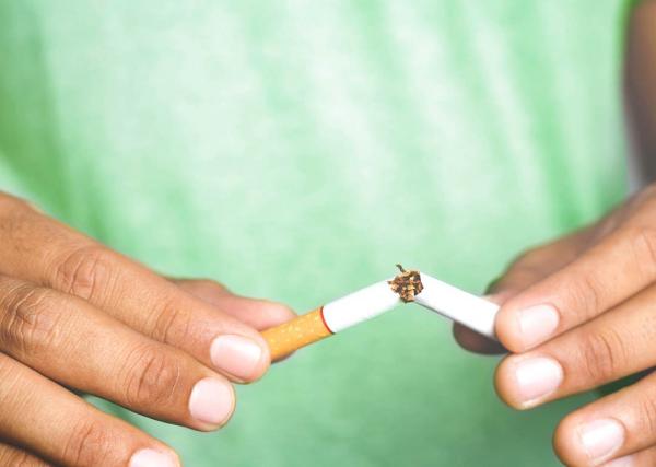 A man breaks a cigarette into two pieces.