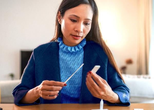 A woman looks at the results of her at-home COVID-19 test.