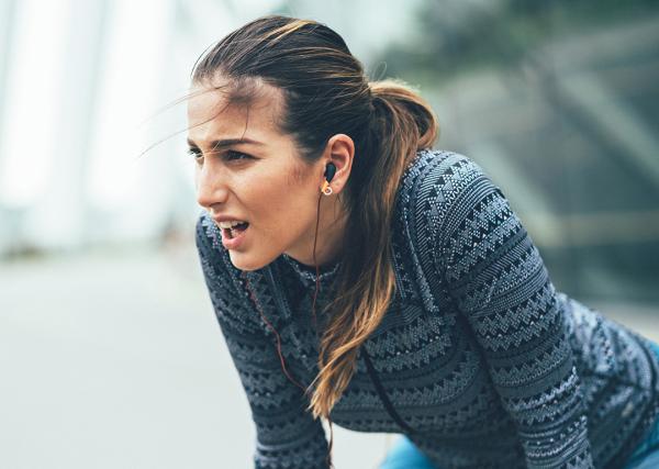 A young woman stops on her run outside to catch her breath.