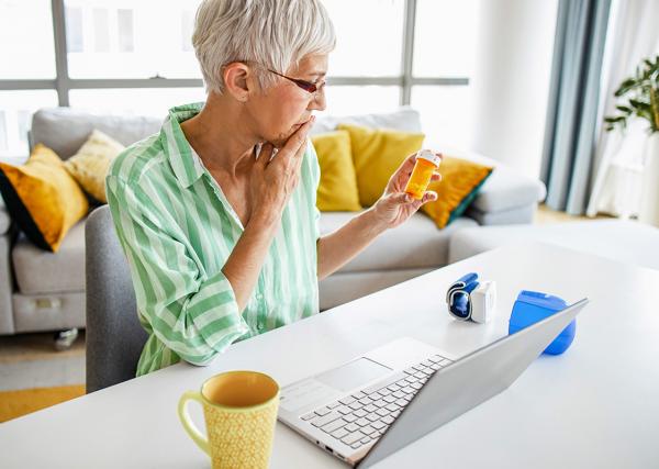 An older woman checks her prescription label to see if her medication has expired.