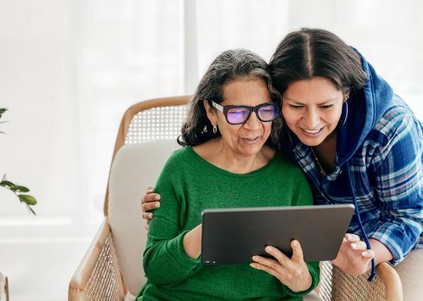 : A young woman and her mother look over a list of her mother’s medications together.