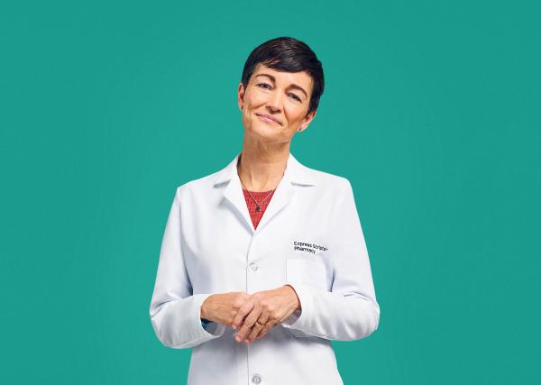 A pharmacist smiles in her Express Scripts® Pharmacy lab coat.