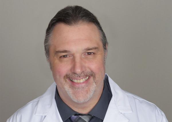 Bill Smith, a registered pharmacist with Express Scripts® Pharmacy, smiles in his white lab coat.