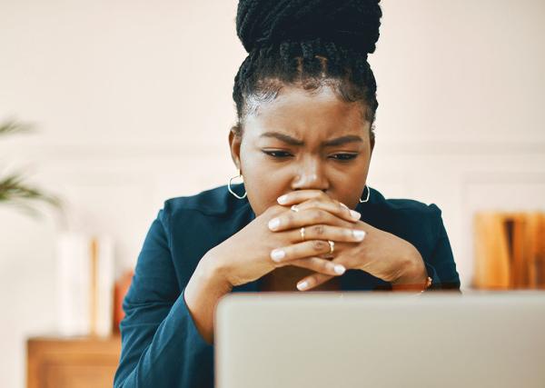 A woman looks at her computer with a concerned expression.