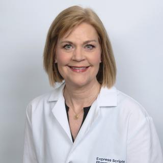 Susan Peppers smiles in her pharmacist lab coat.