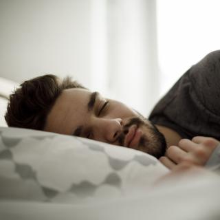 A man sleeps peacefully in his bed as the morning sunlight comes through