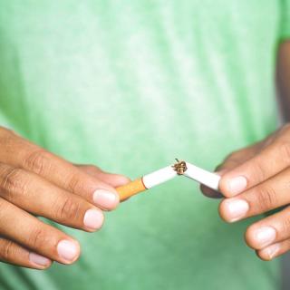 A man breaks a cigarette into two pieces.