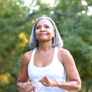 An older woman enjoys a jog outside.