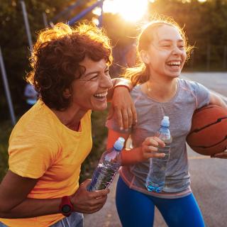 A woman enjoys a water break with her teen daughter and son during a casual basketball game.