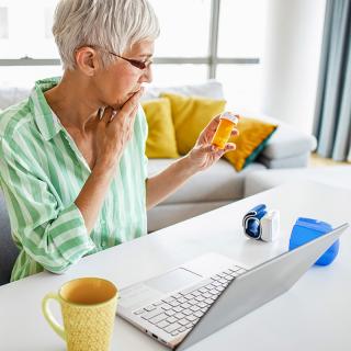 An older woman checks her prescription label to see if her medication has expired.