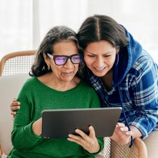 : A young woman and her mother look over a list of her mother’s medications together.