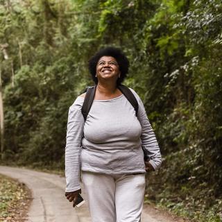 A woman enjoys a walk outdoors on a walking path.