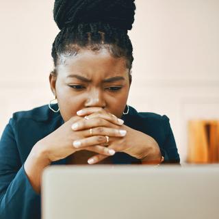 A woman looks at her computer with a concerned expression.